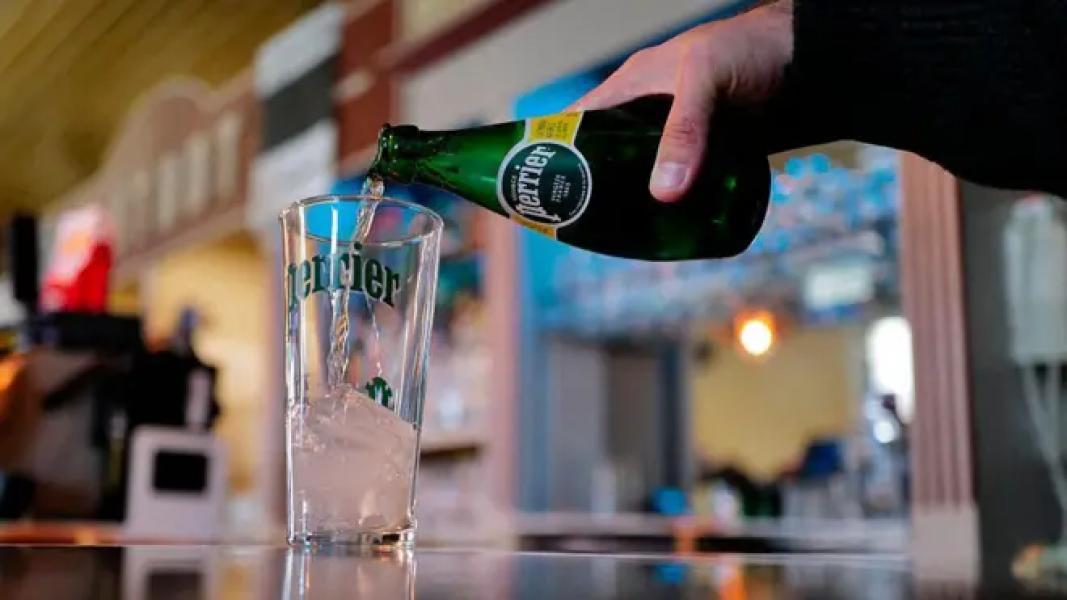 Чоловік наливає воду Perrier у склянку
