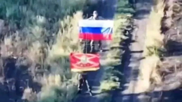 Розмите фото двох чоловіків із російськими прапорами: один триколірний, інший — червоний армійський