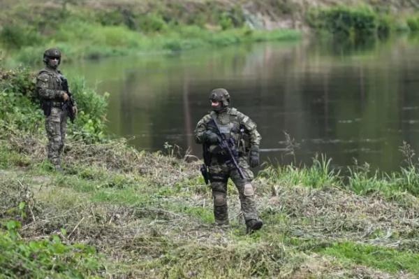 Двоє чоловіків у військовій формі зі зброєю та бронежилетами з написом &quot;Страж Гранічна&quot; (тобто Прикордонна служба) патрулюють берег озера
