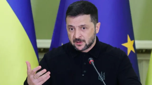 Портрет Зеленського перед мікрофоном на тлі прапорів ЄС і України