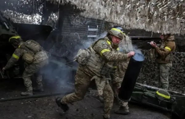 Українські бійці у повному бойовому спорядженні ведуть бої під Куп&#x27;янськом. Один із військових біжить, дивлячись у напрямку камери