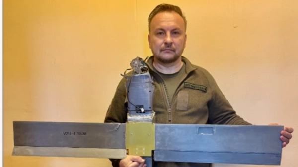 Сергій Бескрестнов - чоловік середнього віку, одягнений у форму кольору хакі. Він тримає в руках дрон з розмахом крил трохи менше півтора метра. Виглядає він доволі грубо зібраним - грубо сконструйованим. Сергій дивиться в об&#x27;єктив камери. 