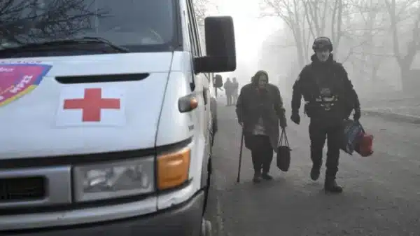 Поліцейський йде поруч з бабусею для евакуації в Гуляйполі