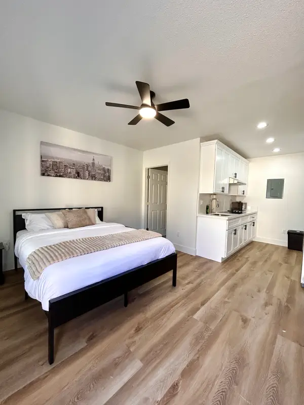 З гаража — ще два Airbnbs: як американка перетворила будинок на чотири прибуткові квартири 8 Сучасна студія з застеленим ліжком, стельовим вентилятором, кухонною зоною, підлогою під дерево та нейтральним декором.