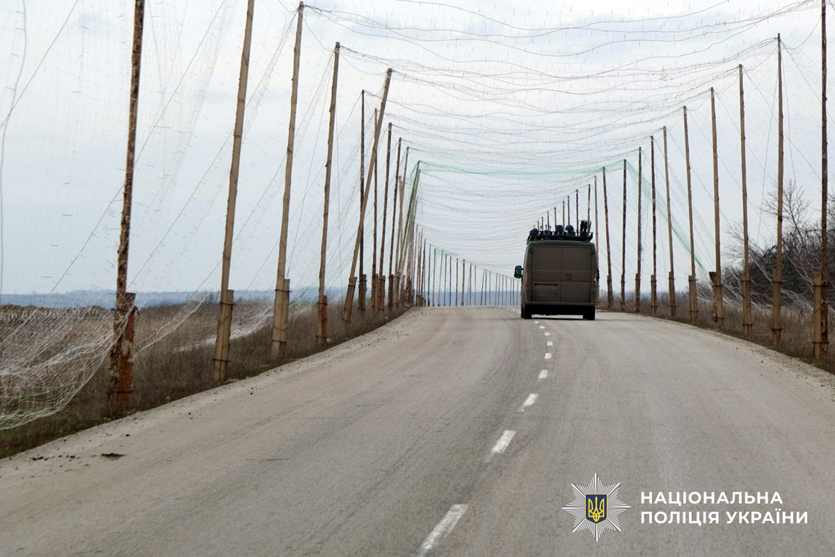 Автомобіль службовців їде дорогою на Донеччині, захищеною сіткою від ударів дронами.