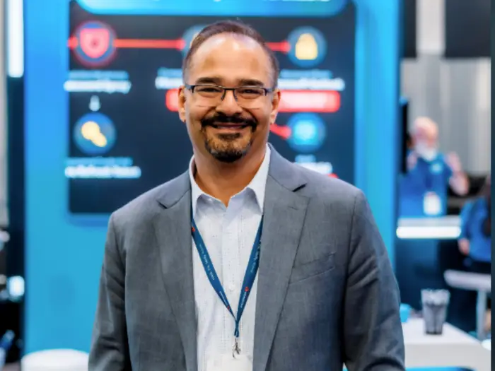 20 років очікування: як співзасновник став мільярдером 2 CEO Horizon3, стартапу в галузі ШІ-хакінгу, посміхається. Він одягнений у темно-синьо-сірий піджак поверх світлої сорочки на ґудзиках.